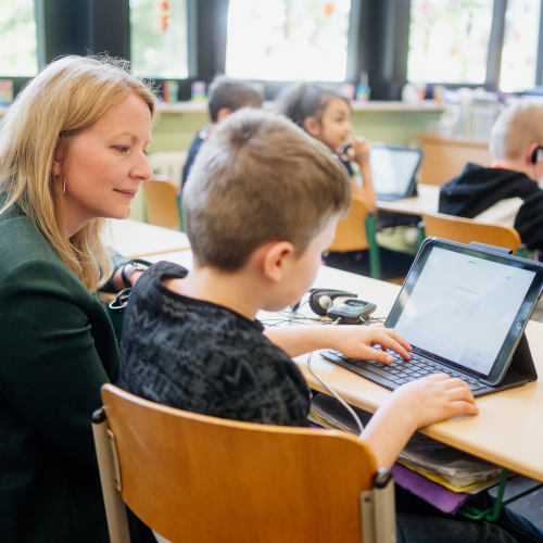 Bild: Ministerin Christine Streichert-Clivot blickt Schulkindern bei Digital-Unterricht über die Schulter. (Copyright: Cuvée - Die Werbewinzer)